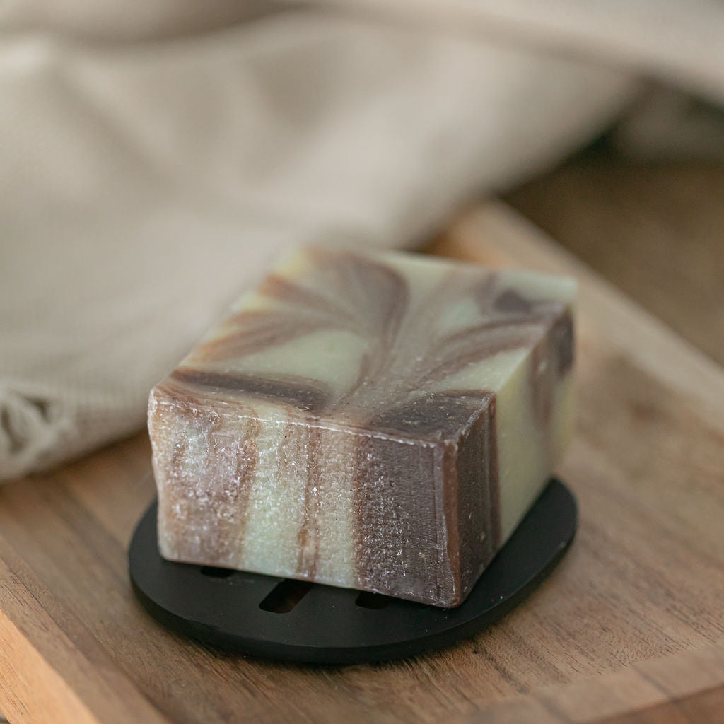 Saltspring Soapworks Cinnamon Vanilla Soap Bar on black soap dish with wooden tray background.