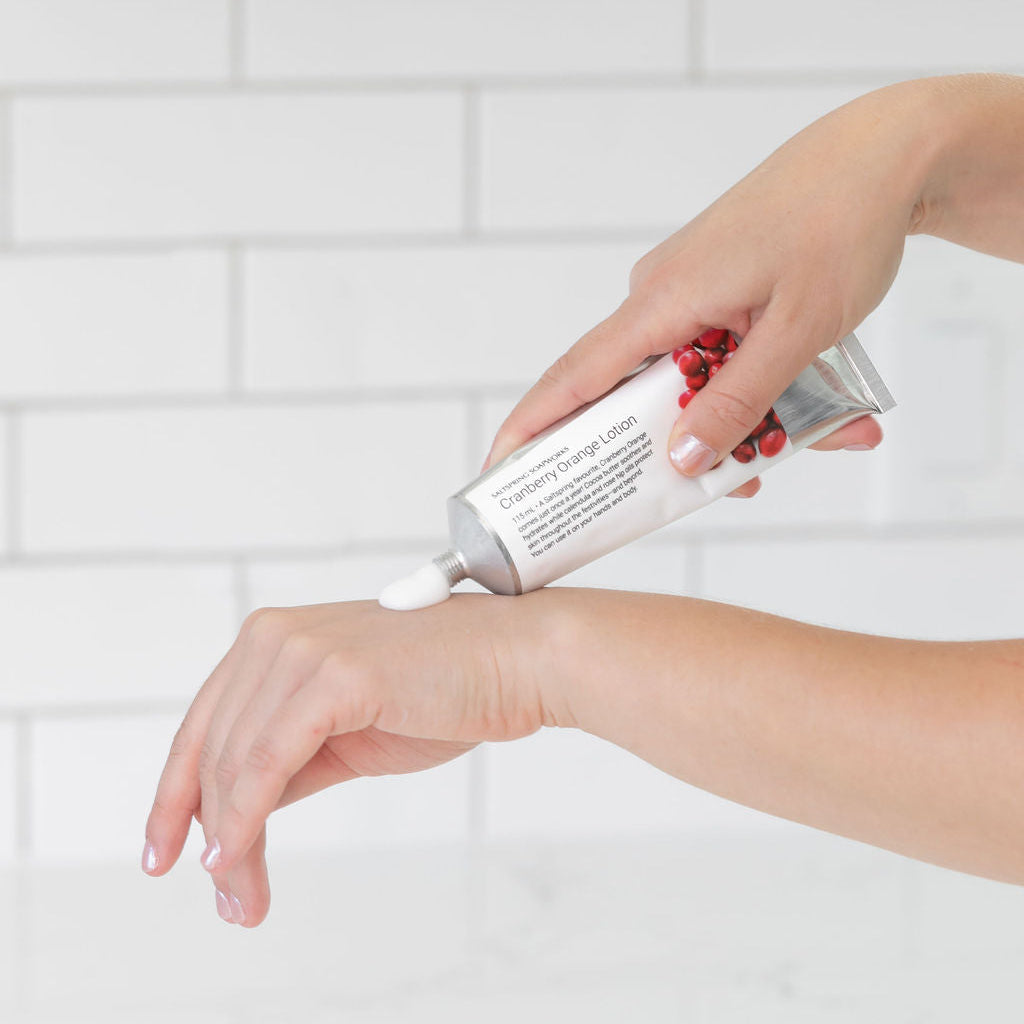Person applying a white cream to their wrist against a light tiled wall background