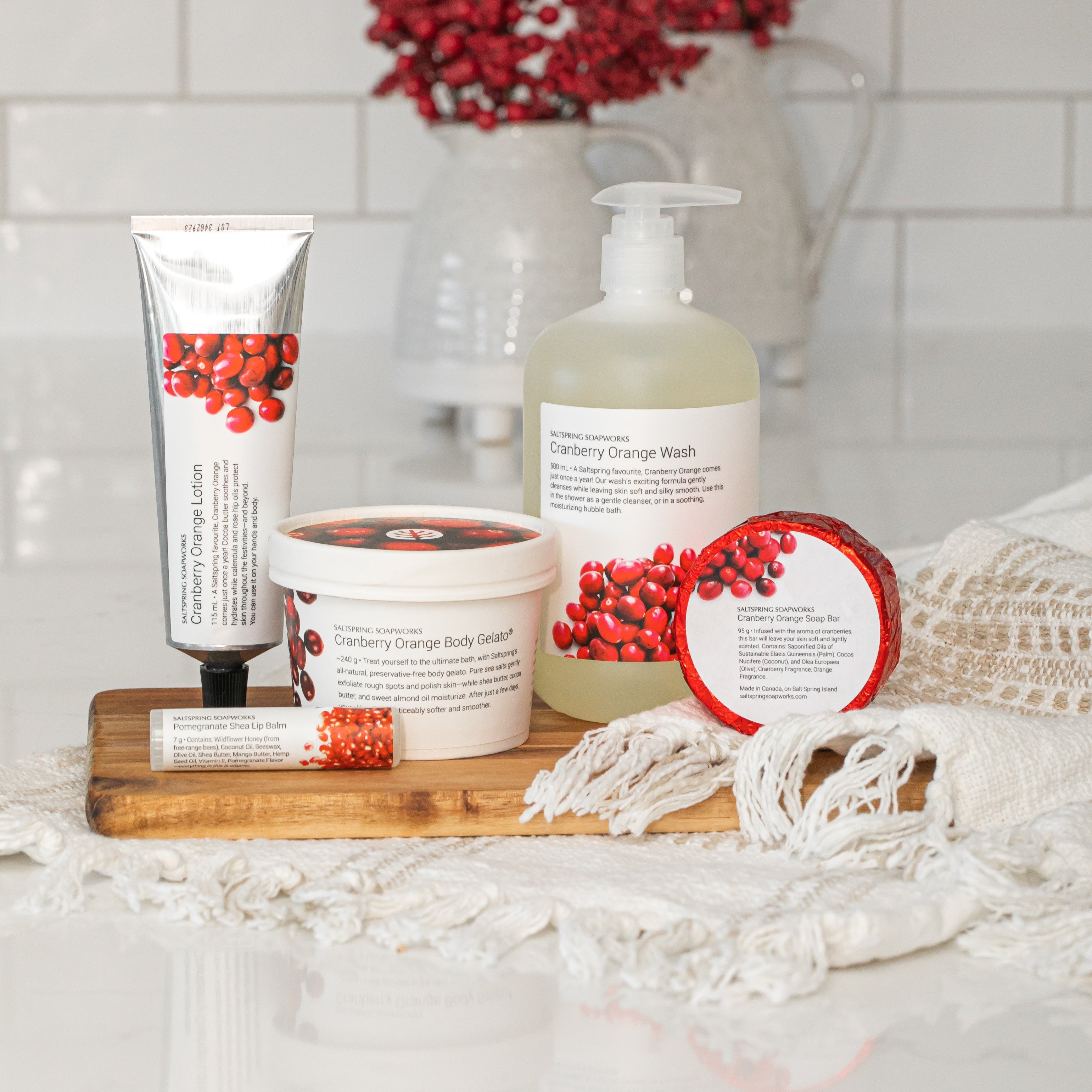 Counter with Cranberry Orange skincare products featuring red berries on a white tiled wall background.