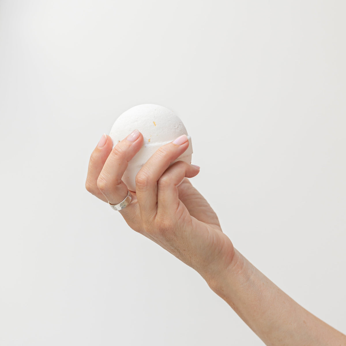hand holding orange vanilla bath bomb