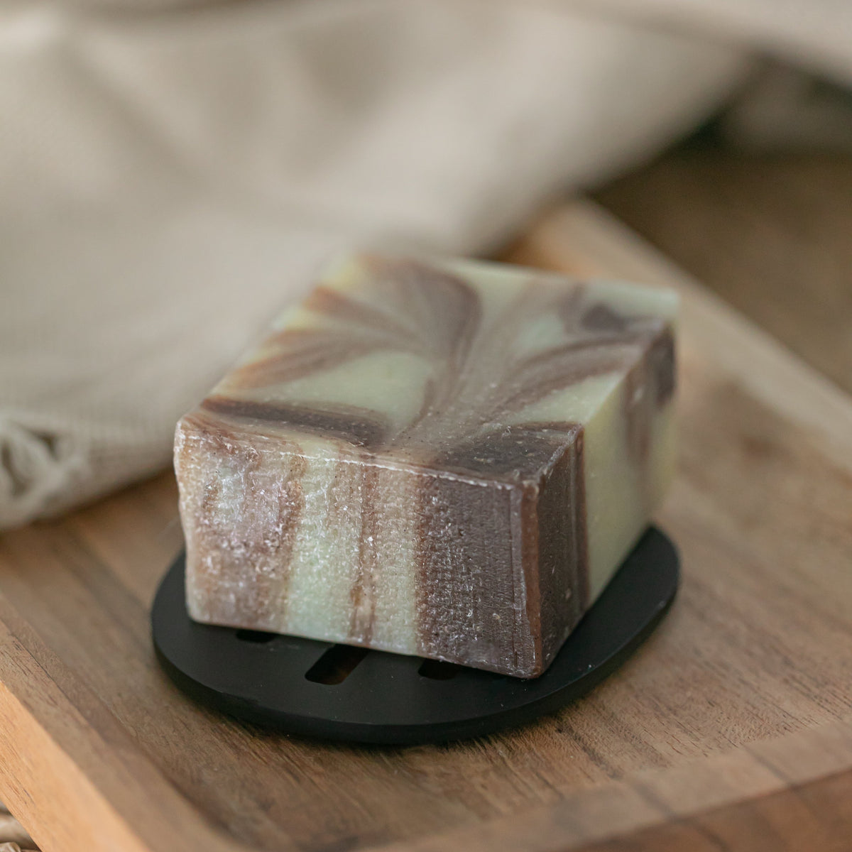 soap bar with brown swirls on black soap saver