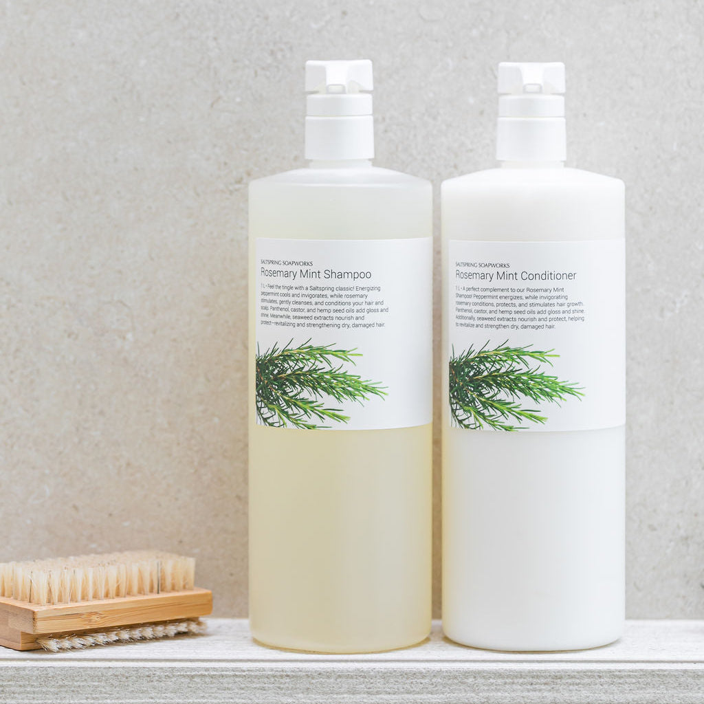 Saltspring Soapworks Rosemary Mint shampoo and conditioner on a tiled bathroom shelf.