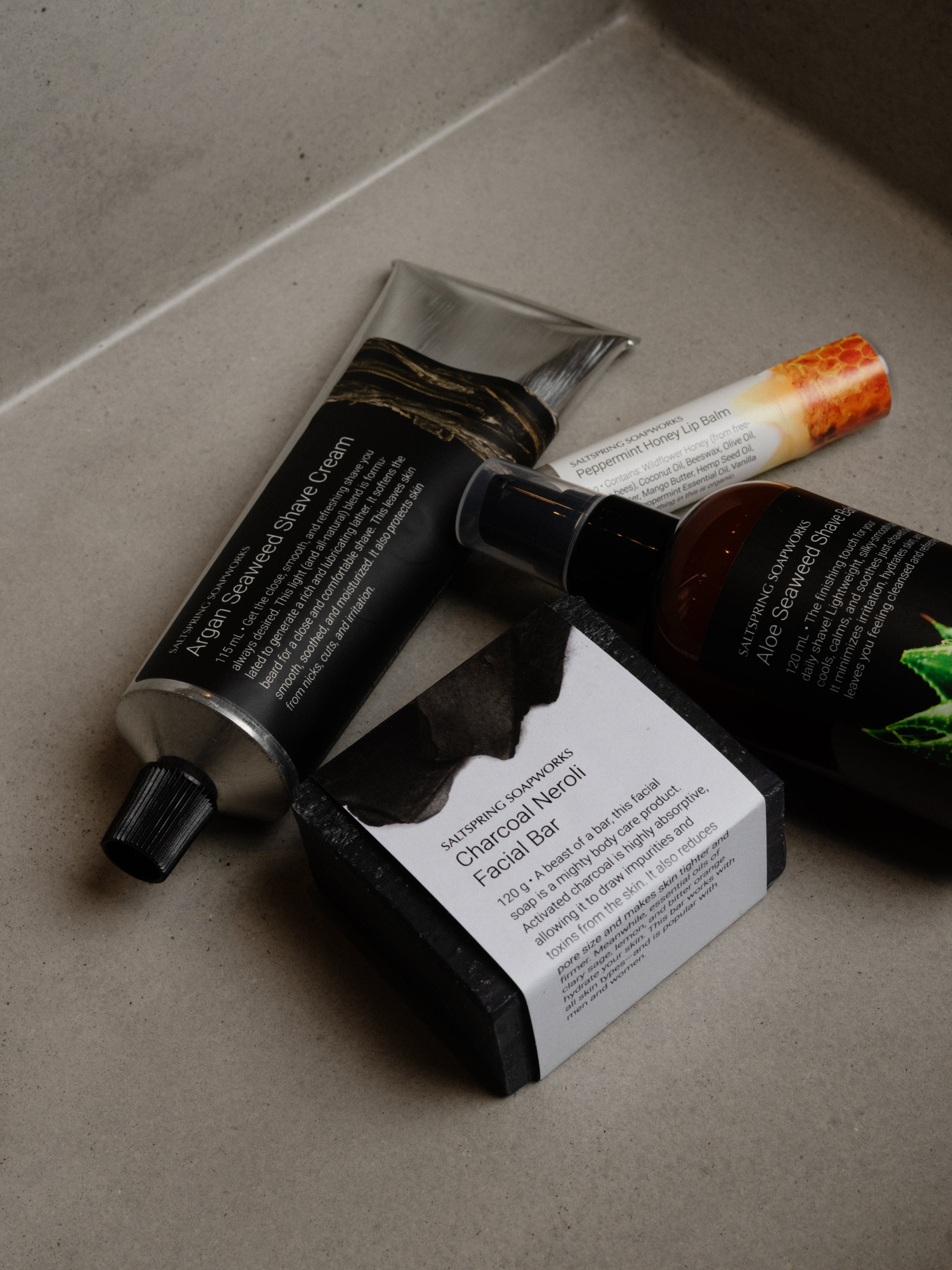 Skincare products including a tube, bottle, and bar on a neutral surface