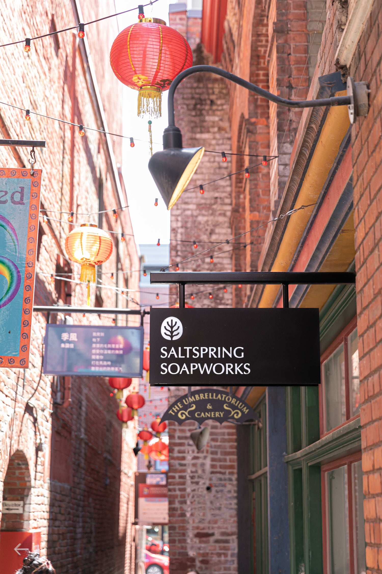 saltspring soapworks store sign amongst lanterns in brick alleyway of Fan Tan Alley