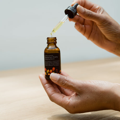 hand holding dropper with Meadowfoam Rosehip Serum dripping out
