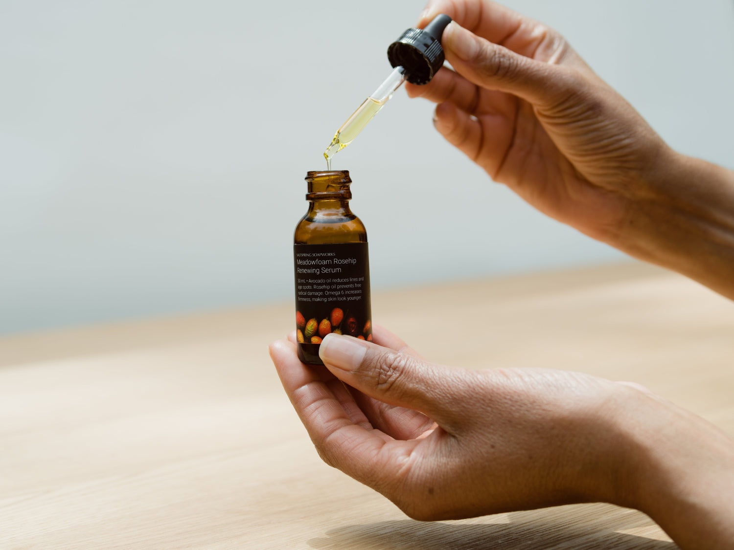hand holding dropper with Meadowfoam Rosehip Serum dripping out