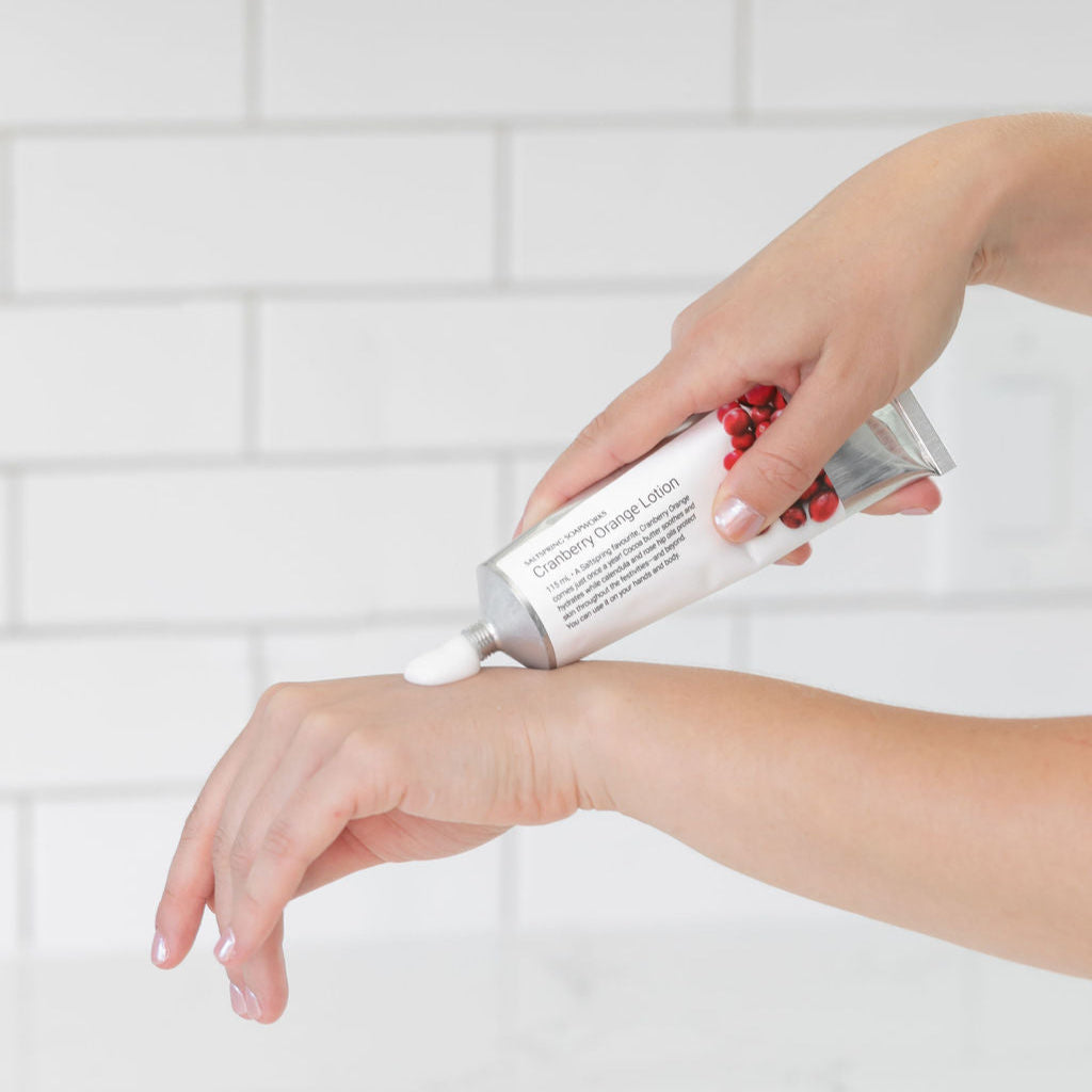 Person applying a white cream to their wrist against a white tiled wall background