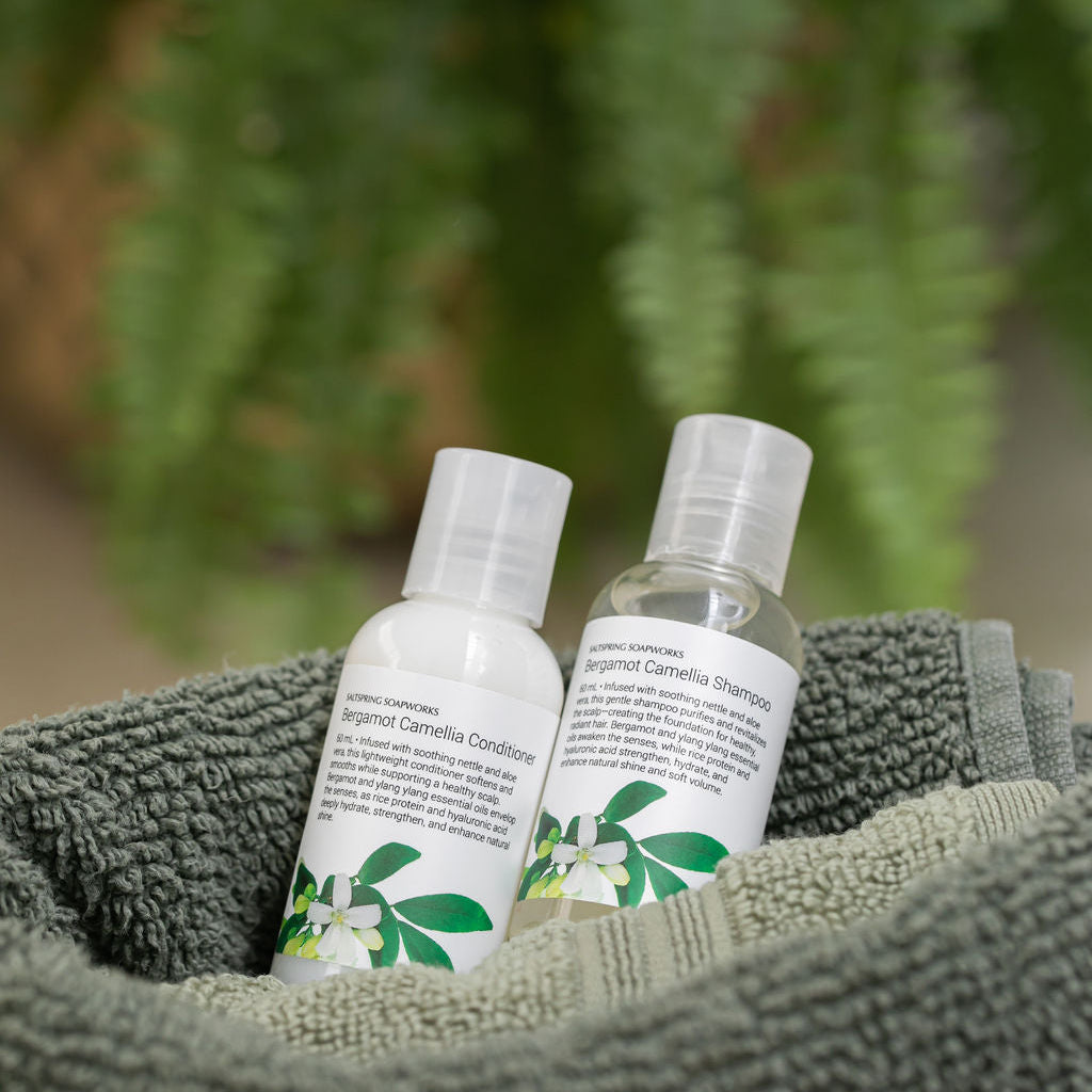 Saltspring Soapworks Bergamot Camellia travel sized bottles shampoo and conditioner sitting on a towel