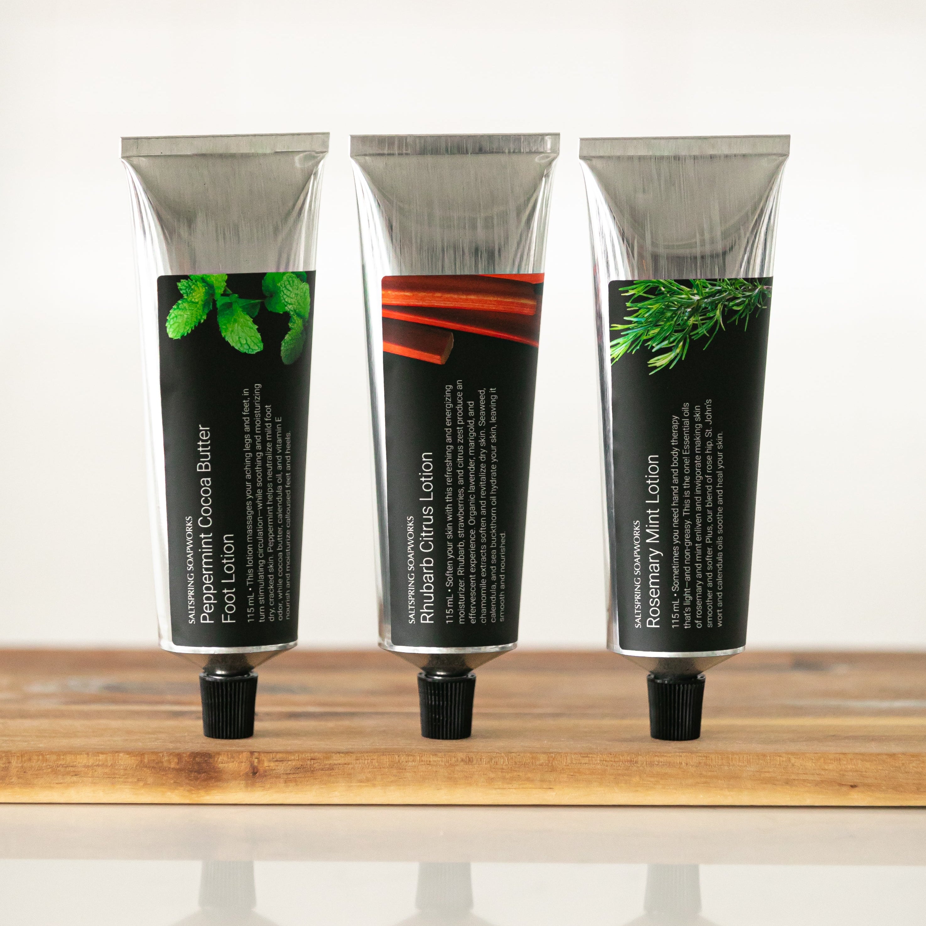 Three tubes of hand cream on a wooden surface with a white background